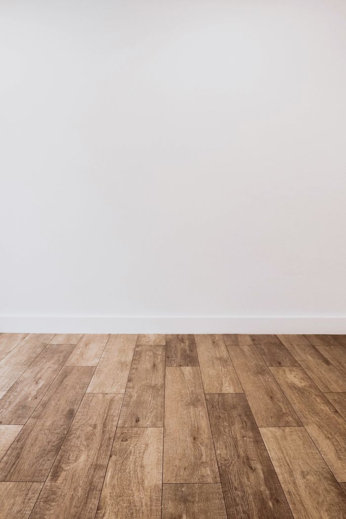 services-01 Clean white wall with wooden flooring offering versatile copy space.