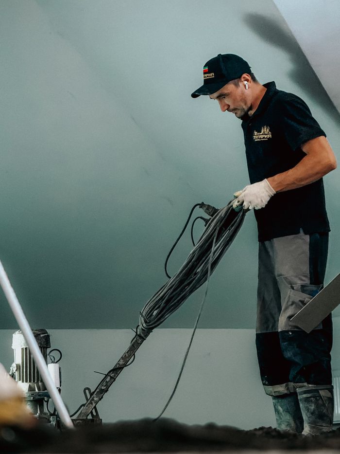 hero-01 Professional construction worker using machinery indoors for flooring or renovation work.