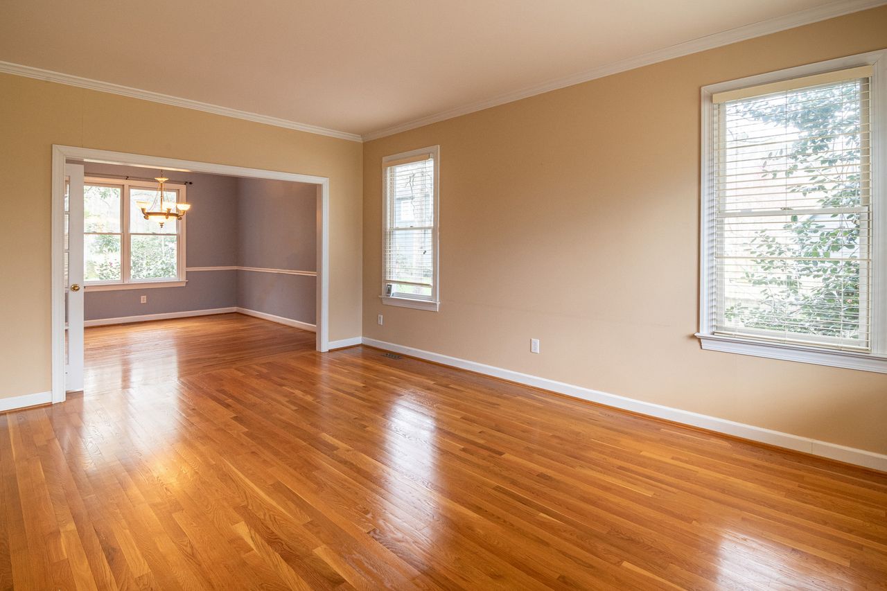 services-01 Bright empty room with wooden floors and large windows, ideal for real estate listings.